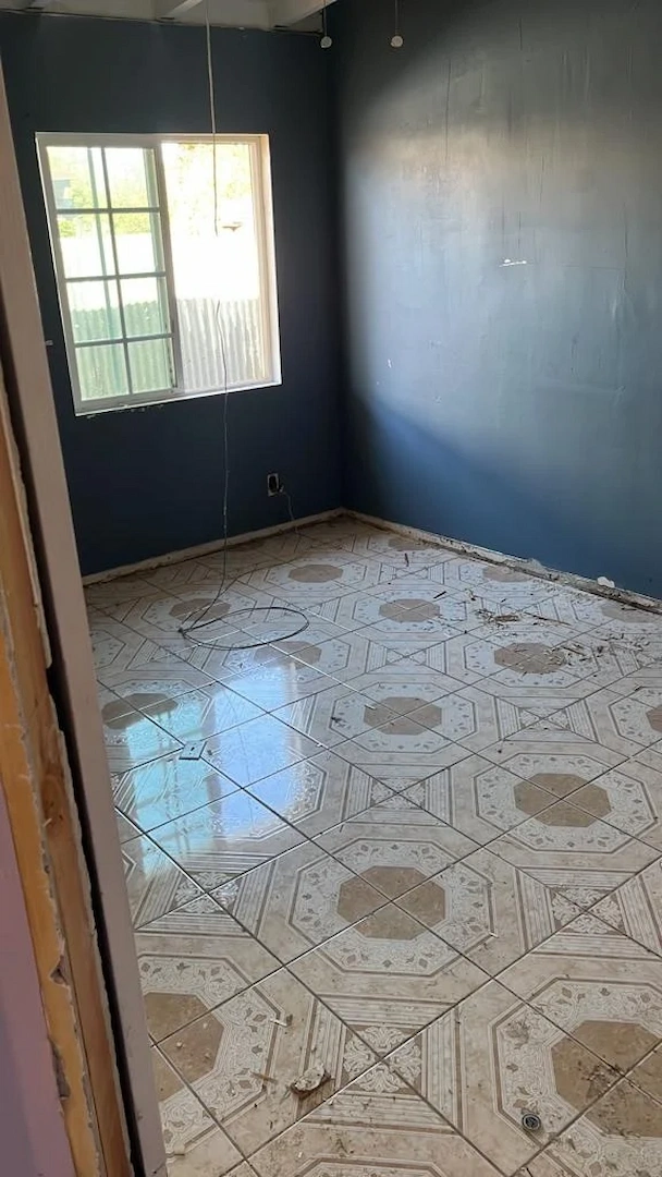 A vacant living room with a freshly painted blue wall and exposed original subfloor in Brea.