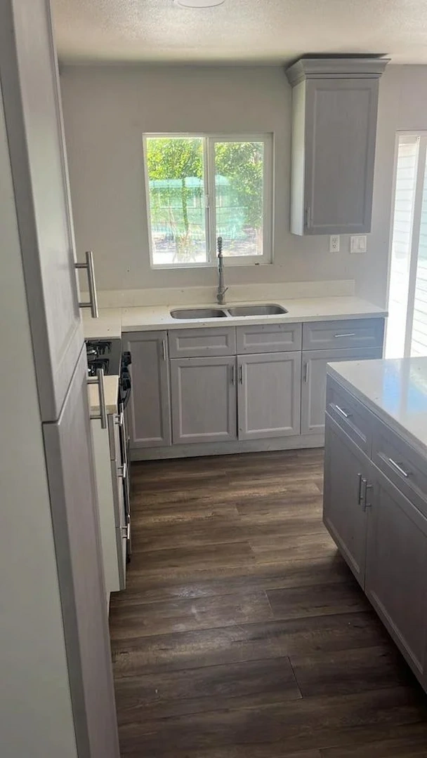 A renovated kitchen with grey shaker cabinets, white countertops, and wood-look flooring in Yorba Linda.
