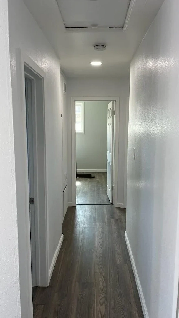 lit renovated hallway with updated white walls and dark wood grain flooring in Anaheim Hills.