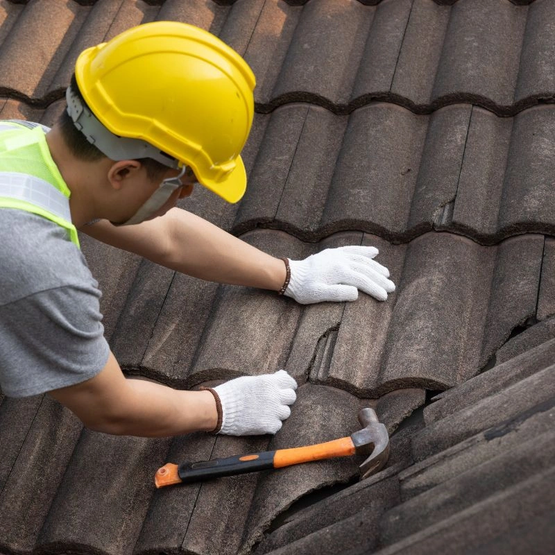A construction worker wearing white gloves and a yellow hardhat inspecting concrete roof tiles in Anaheim Hills.